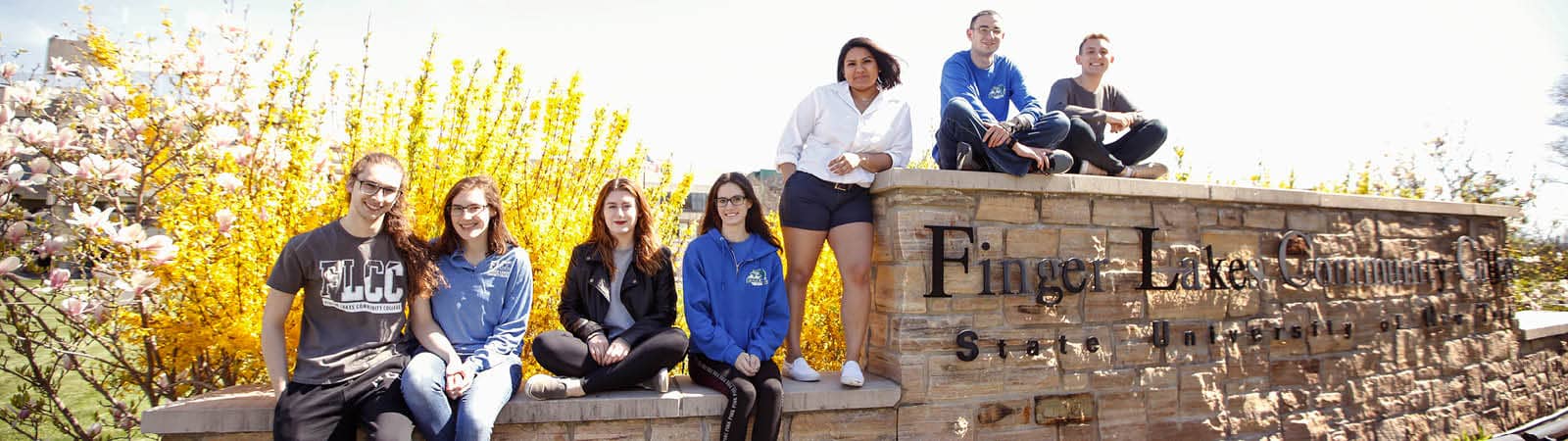 Several students standing near the FLCC sign on main campus.