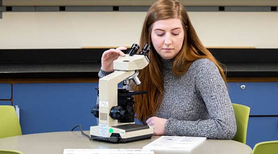 Student in a classroom using a microscope