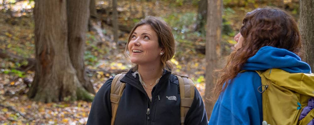 Two FLCC students backpacking through a forest. They pause momentarily to take in the beauty of the natural scene.